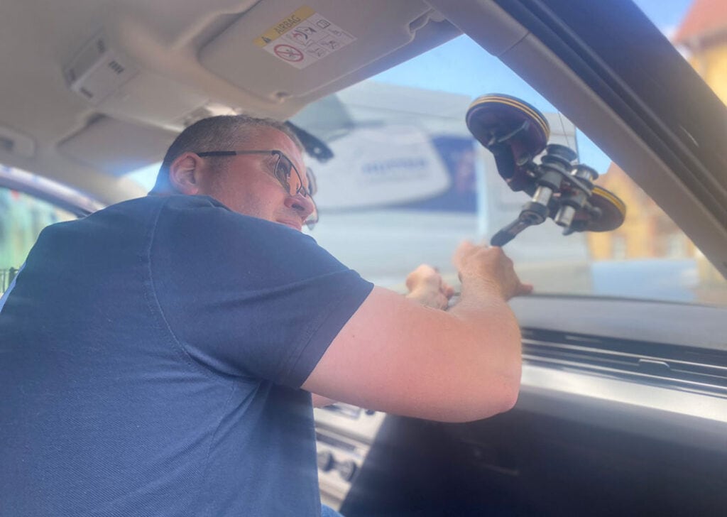 Mann im auto an der frontscheibe mit saugnapfgriff zum